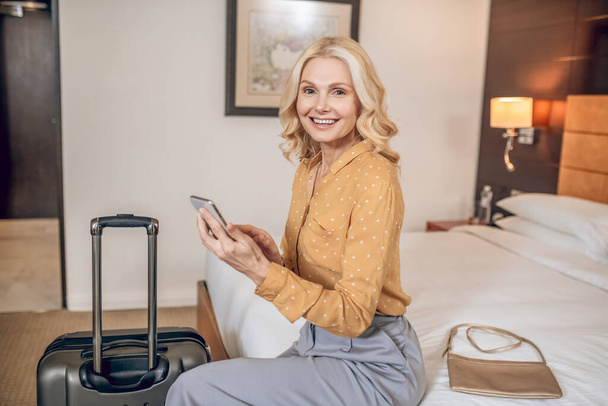 Elegant blonde woman in grey pants in a hotel room - Fotoğraf, Görsel