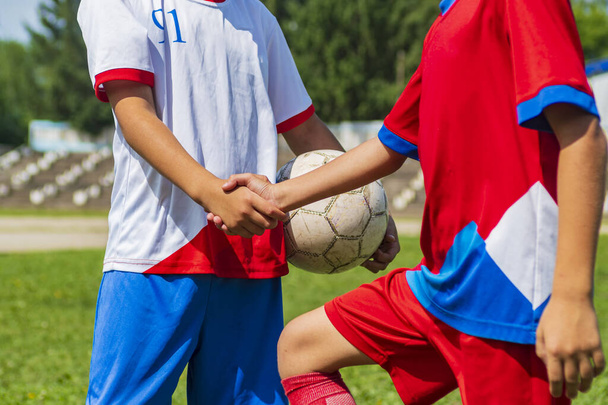A close-up of the cropped bodies of young soccer players. Children shake hands before the start of the match. Sports greeting. - Photo, image