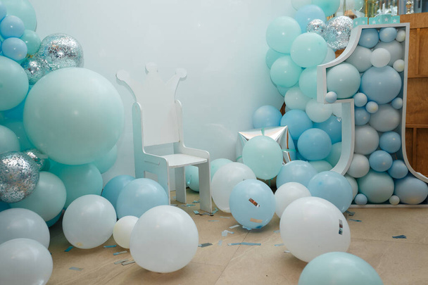 Μπλε μπαλόνια για το πάρτι γενεθλίων του αγοριού. Νούμερο 1 για ένα παιδί. Γιορτινά διακοσμητικά στοιχεία, ζώνη φωτογραφιών με καρέκλα.  - Φωτογραφία, εικόνα