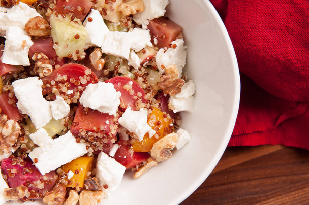 An overhead shot of heirloom tomato, apple, walnut, beets, and quinoa salad with feta cheese - Photo, Image