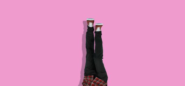 simple human legs in sneakers upside down against the colorful wall, trendy chill and relax concept wide webn banner - Фото, изображение