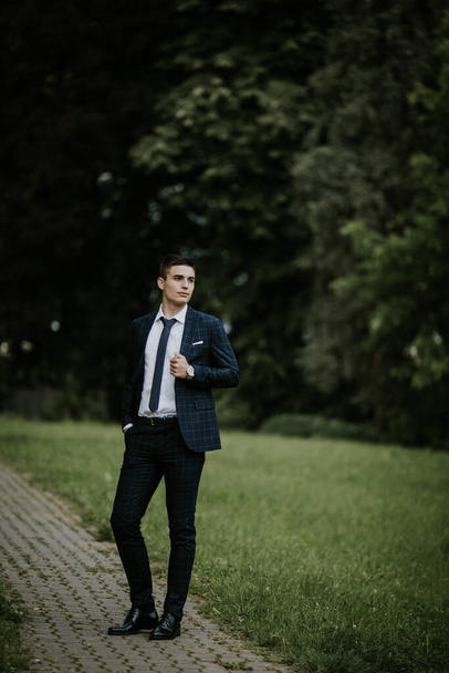 A caucasian young businessman in a suit and tie standing in the park - Foto, Imagem