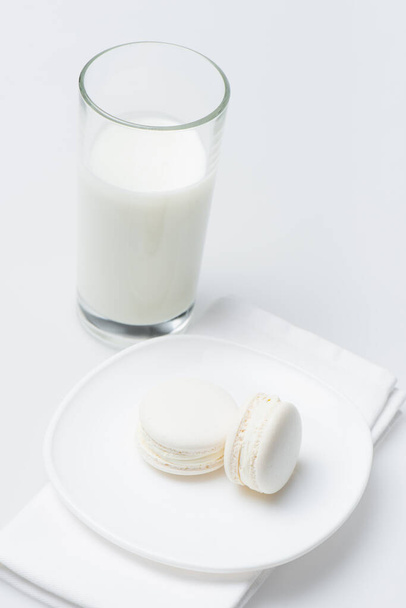 delicious macarons on plate near glass of milk isolated on white - Photo, image