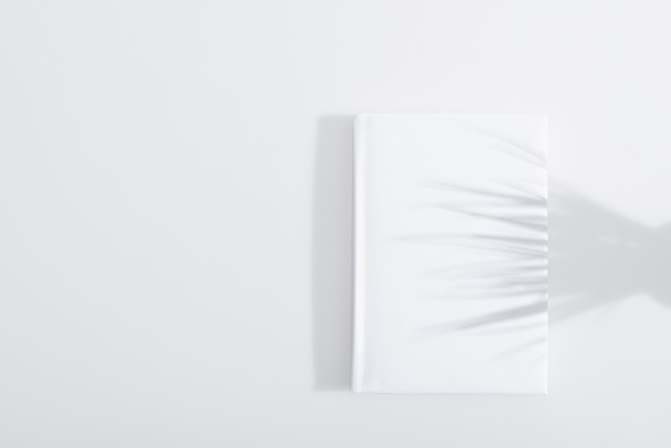 тень на твердой обложке книги на белом фоне - Фото, изображение