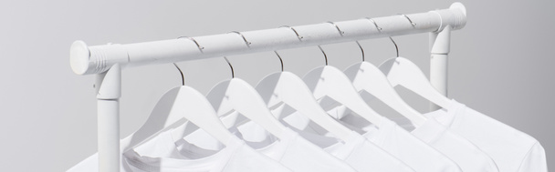 collection of white t-shirts hanging on clothes rack isolated on grey, banner - Photo, Image