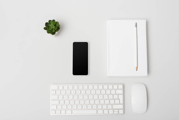 flat lay with smartphone near computer mouse, keyboard, notebook and plant isolated on white  - Foto, afbeelding