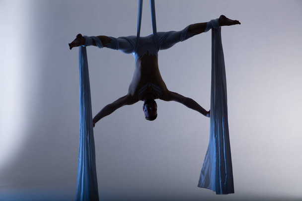 Couple of beautiful aerial gymnasts from Ukraine "Duo lotos" flying on fabric ropes and circle, performing aerial exercise with white fabrics on white background - Fotoğraf, Görsel