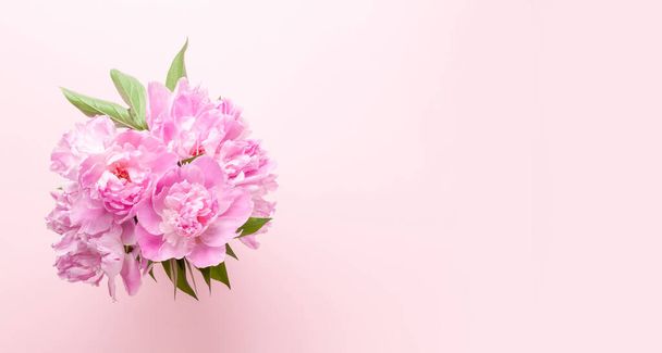 Beautiful garden peony flowers bouquet on pink background. Top view flat lay with space for your holiday greetings - Photo, Image