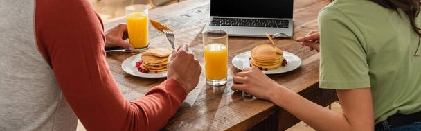 Cropped view of couple having breakfast with pancakes near laptop, banner  - Foto, imagen