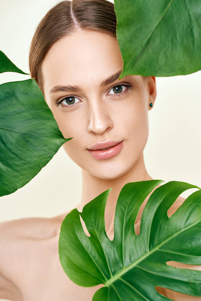 Close up portrait of young beautiful woman with perfect smooth skin in tropical leave - Photo, Image