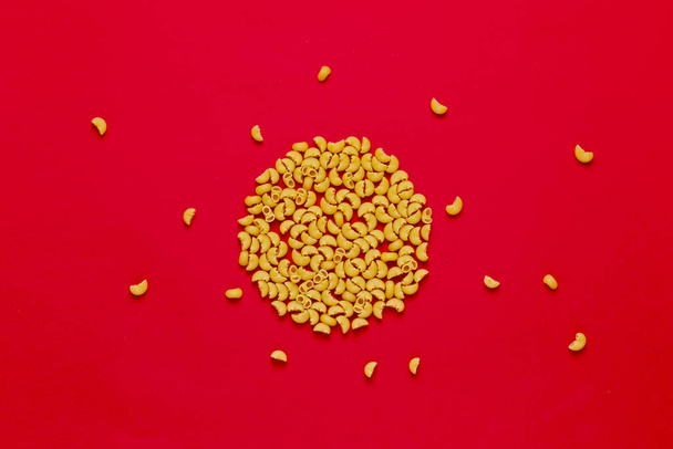 a bunch of simple raw macaroni pasta flat lay on the colorful surface table - Foto, Imagen