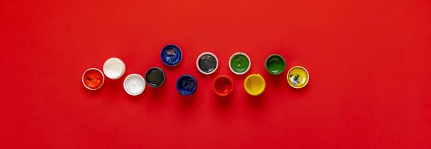 una vista dall'alto delle vernici colorate guazzo in vasi o lattine sullo sfondo colorato ampio banner lungo - Foto, immagini