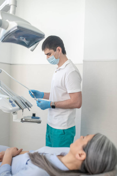 Dentista masculino en máscara protectora preparándose para la restauración de dientes - Foto, Imagen