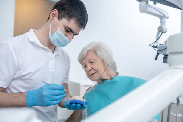 Hombre dentista hablando con su paciente de senipr y explicando su diagnóstico - Foto, imagen