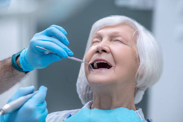 Dentista em luvas estéreis trabalhando com um paciente em seu consultório - Foto, Imagem