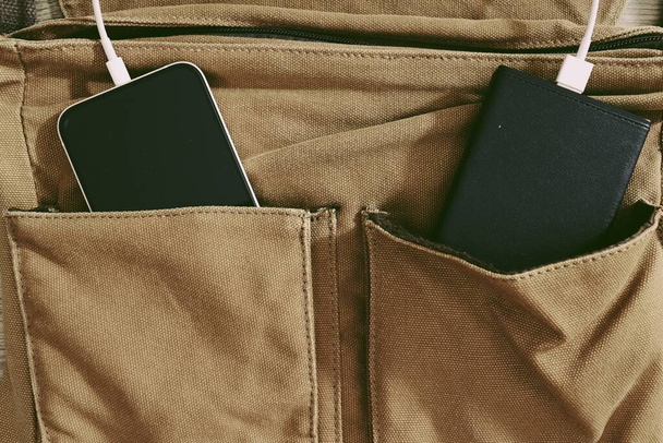 Strombank-Ladegerät und Smartphone mit brauner Tasche auf Holztischhintergrund - Foto, Bild