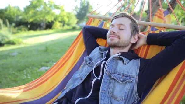 Giovane uomo felice rilassante in amaca in giardino - Filmati, video