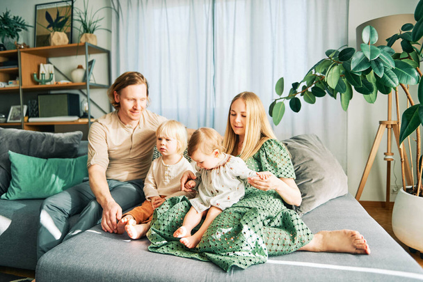 Feliz familia joven de cuatro que se relaja en un sofá, pareja jugando con la niña y niño pequeño - Foto, imagen