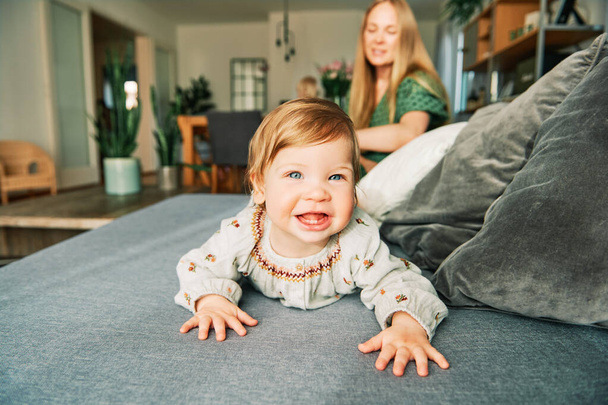 Happy young mother playing with adorable toddler girl, resting on a couch in living room - Foto, Imagen
