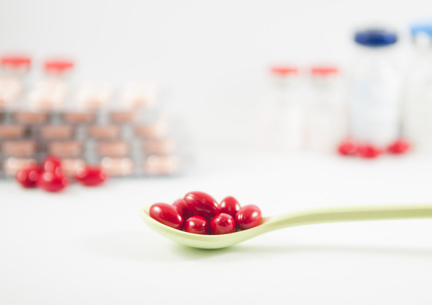 Punainen tabletti lusikassa lääketaustalla
 - Valokuva, kuva