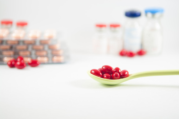 Pastillas rojas en cuchara sobre fondo del medicamento
 - Foto, Imagen