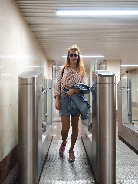 Chica sonriente pasa por el torniquete de hierro en la estación de tren - Foto, imagen