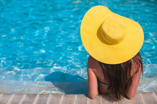 Nainen keltainen hattu rentouttava uima-altaalla eksoottisessa keinona
 - Valokuva, kuva