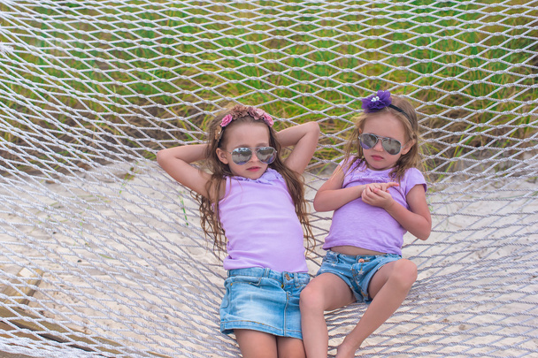 μικρά γλυκά κορίτσια χαλαρώνοντας στην αιώρα σε καλοκαιρινές διακοπές - Φωτογραφία, εικόνα