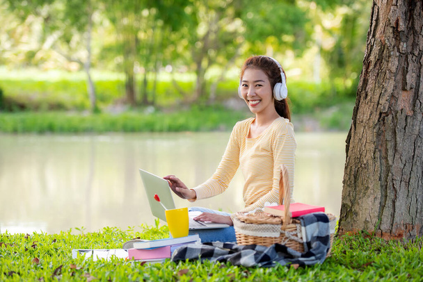 Young people work from home with laptop and drinking coffee in morning relax at nature garden home. Asia woman meeting conference connect online with office.  Business and Technology Concept - Foto, Imagen