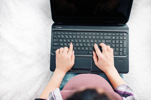 Mujer embarazada sentada en la cama trabajando en el ordenador portátil en casa, vista superior. - Foto, imagen