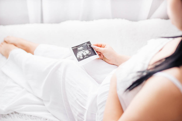 Kobieta w ciąży patrzy na zdjęcie USG. - Zdjęcie, obraz