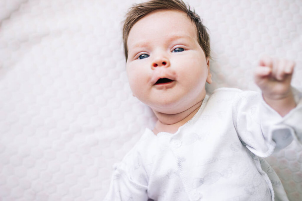 newborn baby girl with beautiful blue eyes lying on the bed close up. - Φωτογραφία, εικόνα