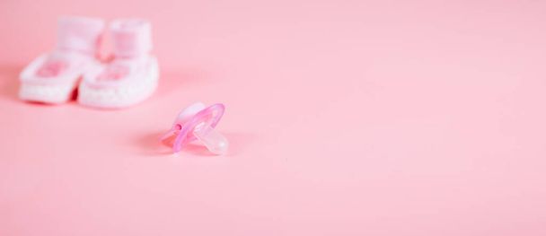 Orthodontische fopspeen in roze kleur, geïsoleerd op een roze achtergrond. Toont tekenen van gebruik. Ruimte voor tekst op een dummy-achtergrond. - Foto, afbeelding