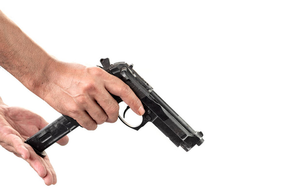 Close-up of a man's hand holding and loaded a magazine in a gun isolated white background. - Zdjęcie, obraz