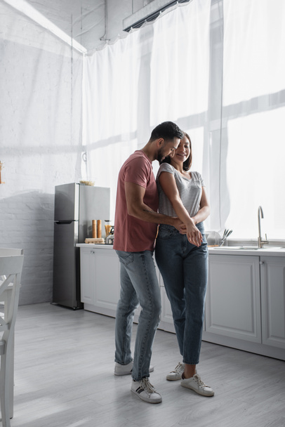 positive young couple in casual clothes dancing in modern kitchen - Fotografie, Obrázek