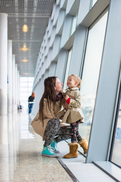 Mother and little daughter looking out the window at airport terminal - Photo, Image