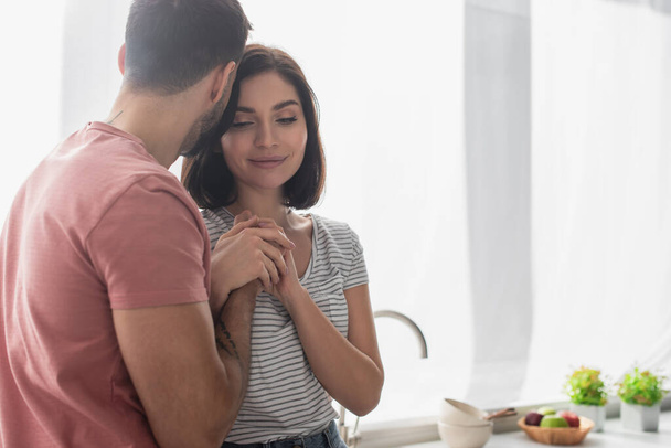 young brunette couple gently holding hands in kitchen - Photo, Image