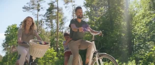 Bodem uitzicht op speelse familie fietsen in het bos. Opgenomen met RED helium camera in 8K. - Video
