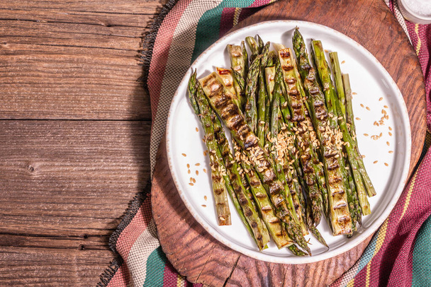 Ripe grilled asparagus. Rustic style arrangement, healthy food concept. Trendy hard light, dark shadow. Vintage wooden boards, top view - Photo, Image