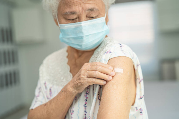 Sujets âgés Asiatique femme âgée portant un masque facial se faire vacciner covid-19 ou coronavirus par un médecin faire l'injection. - Photo, image