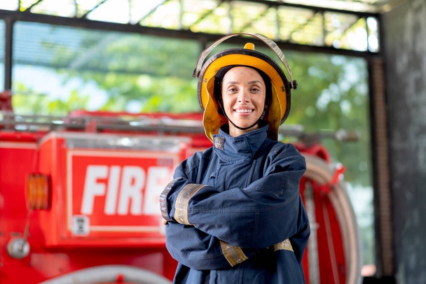 Strażak z ubraniami ochronnymi stoją z akcji zaufania i uśmiech przed wozem strażackim. Ona również uśmiecha się ze szczęścia i miłości do pracy w tej pracy. - Zdjęcie, obraz