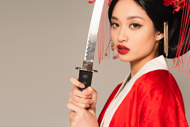 Ασιάτισσα γυναίκα με κιμονό κρατώντας σπαθί απομονωμένο στο γκρι  - Φωτογραφία, εικόνα