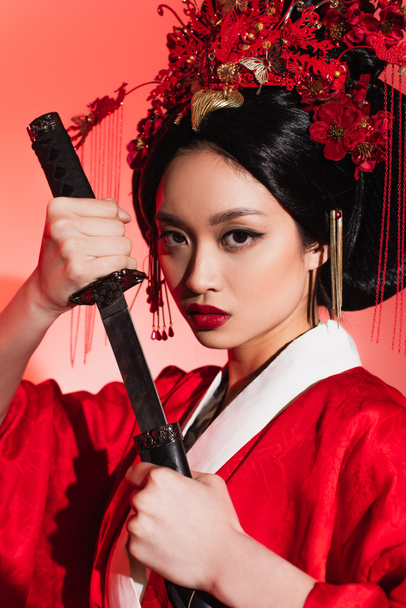 Portrait of asian woman with sword and sheath on red background  - Fotoğraf, Görsel