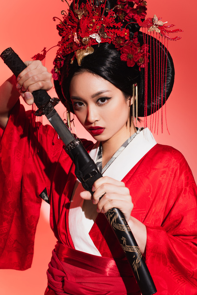 Young asian woman holding sheath and sword on red background  - Foto, Imagem