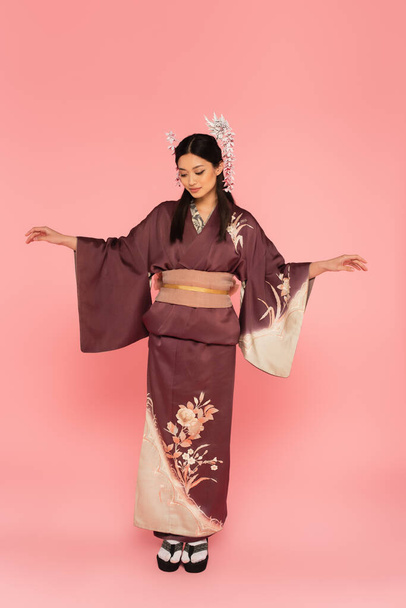 Full length of asian woman in oriental wear standing on pink background - Photo, Image