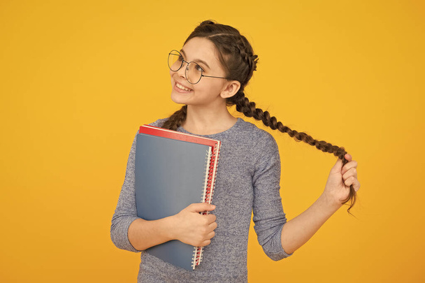 Flights of imagination. Girl with long plaits hold books. Little dreamer with thoughtful look yellow background. Imagination and fantasy. Developing imagination. Learning with imaginaiton matters - Valokuva, kuva