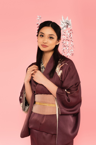 Pretty japanese woman with kanzashi in hairdo looking at camera isolated on pink  - Photo, Image
