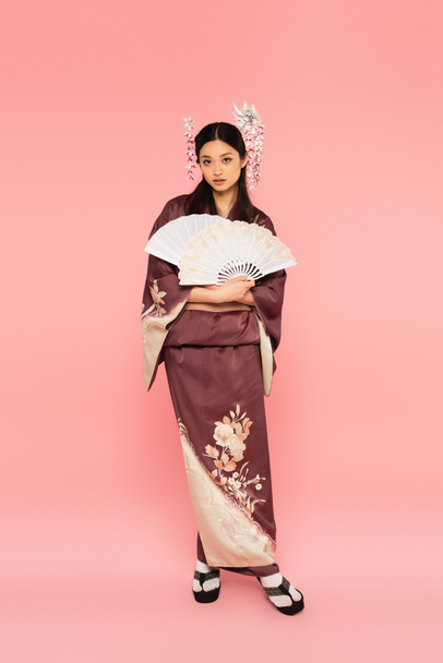 Pretty asian woman in traditional clothes holding fans on pink background - Valokuva, kuva