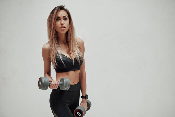Fitness-Modell mit Hanteln vor weißem Hintergrund - Foto, Bild