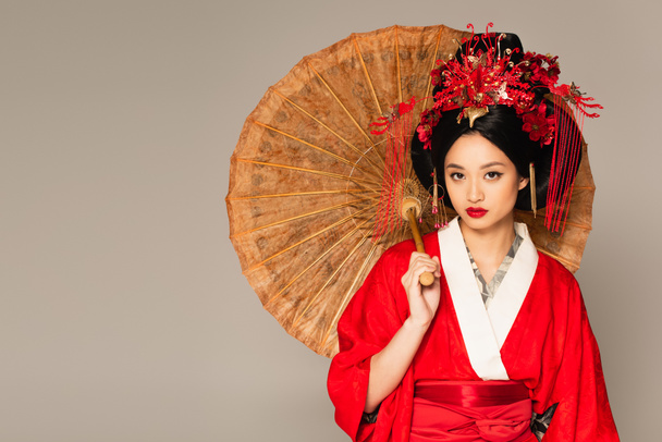 Japanese woman with red lips holding umbrella isolated on grey  - Fotografie, Obrázek